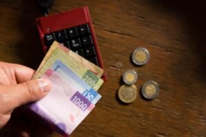 billetes mexicanos y calculadora sobre mesa madera