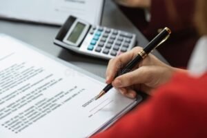 manos firmando contrato laboral y calculadora