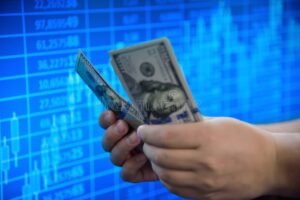 manos sosteniendo billetes y grafico financiero