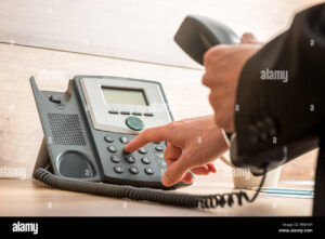 persona haciendo llamada telefonica usando telefono fijo