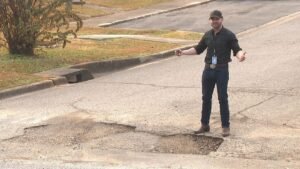 vecino senalando calle con baches grandes